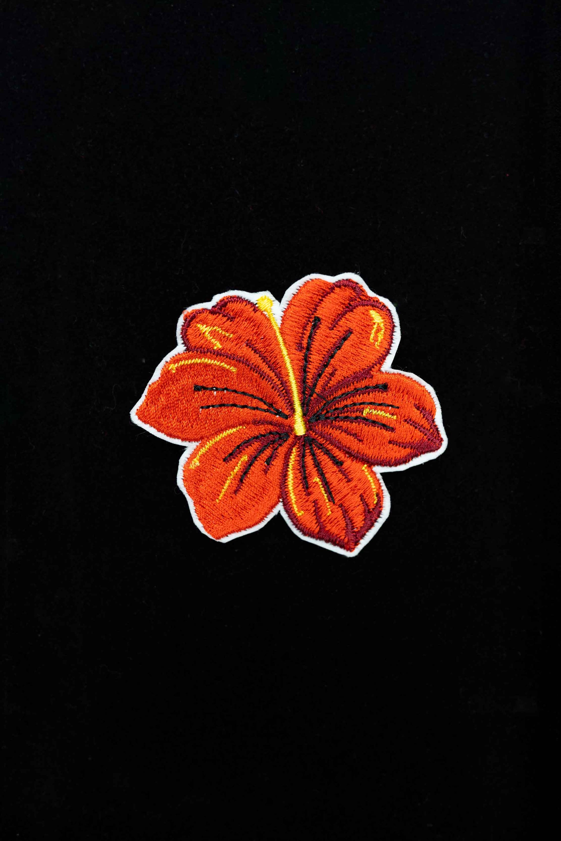 An embroidered hibiscus flower brooch, ideal for adding a splash of tropical elegance and color to your style.