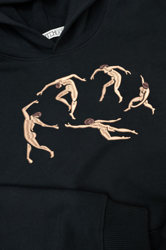 A black hoodie featuring an embroidered design inspired by Matisse's "The Dance." The embroidery depicts five abstract human figures in motion, stitched in a beige tone with brown hair, forming a circular composition. The hoodie has a soft texture, a visible front pocket, and a slightly folded hood, with a stitched label at the neckline.