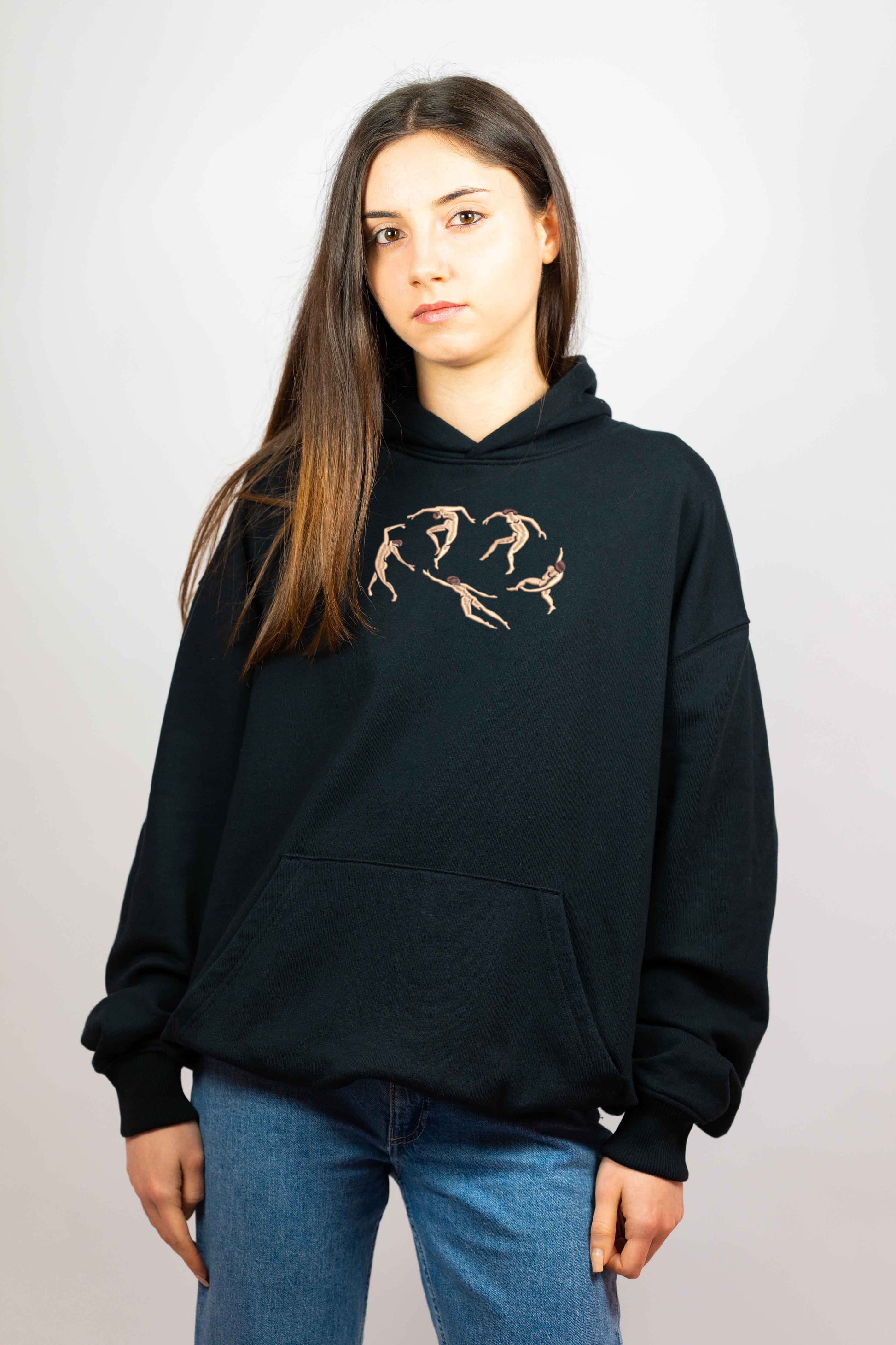 Minimalist embroidered hoodie featuring a Matisse-inspired design of five abstract human figures in motion. The beige and brown stitching contrasts against the black fabric, creating a vintage aesthetic.