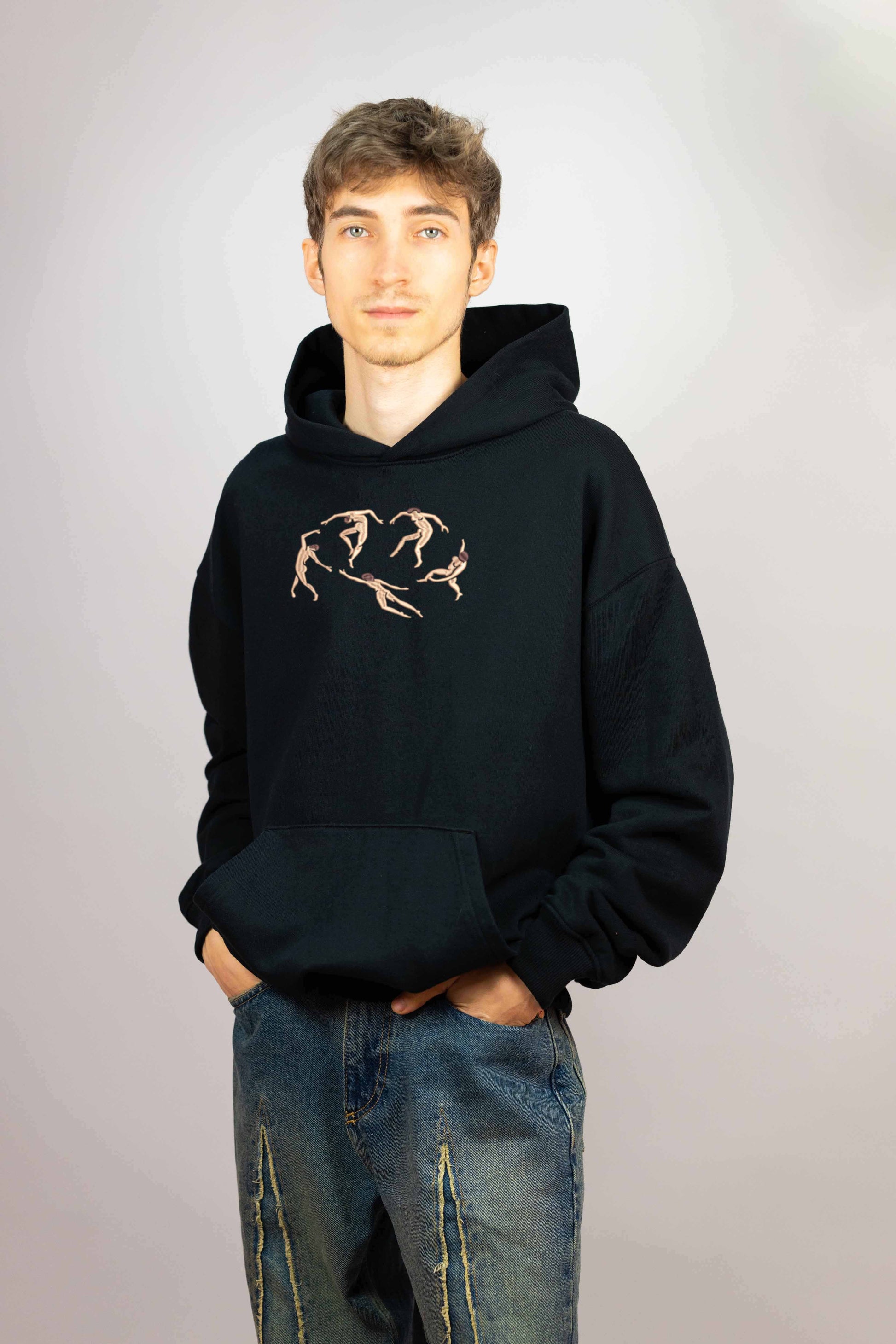 Black organic cotton hoodie with intricate embroidery depicting a reimagined version of Matisse’s "The Dance." Five stylized figures with flowing movements form a circular pattern.