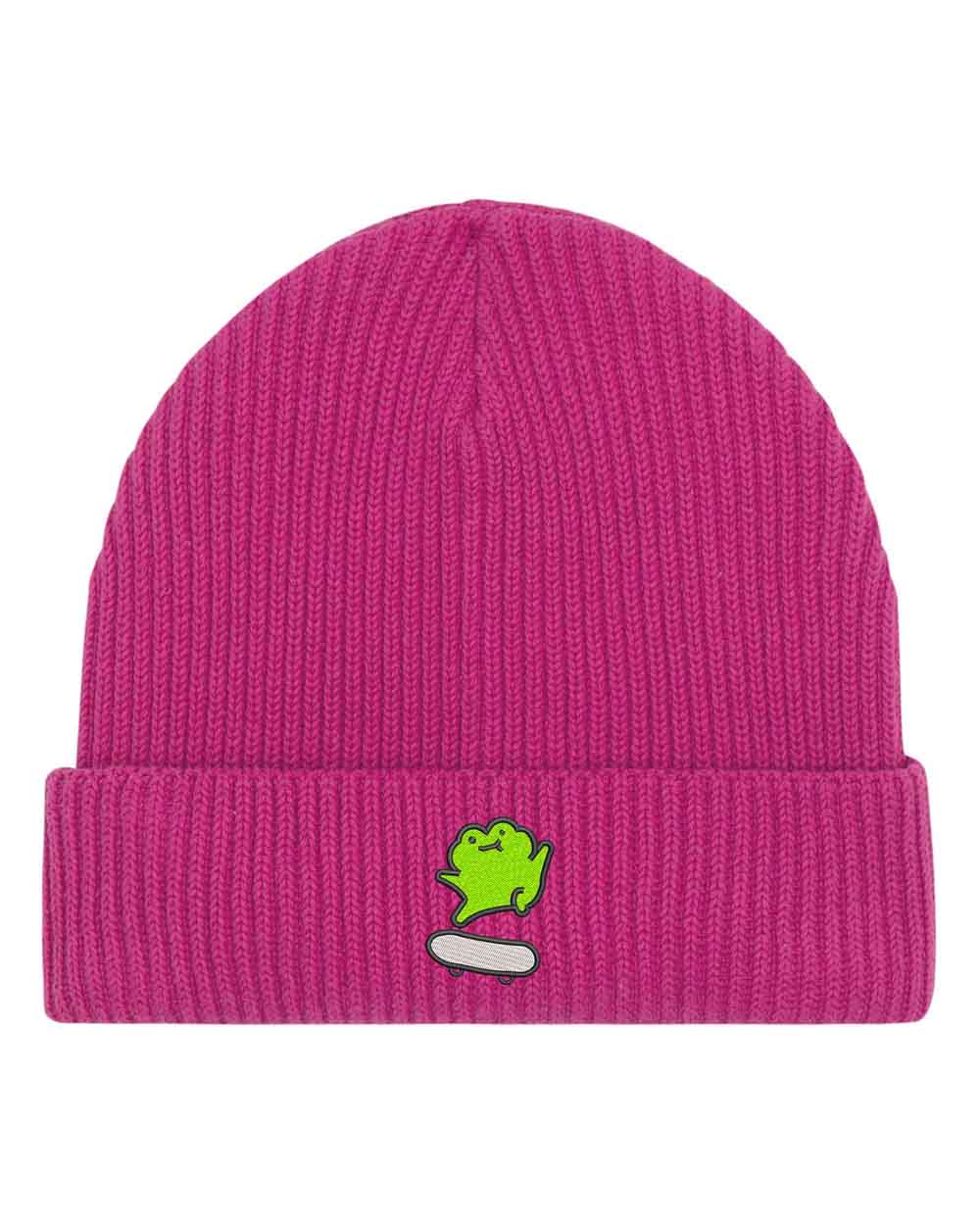 Căciulă roz din tricot cu manșetă întoarsă, brodată cu o broască simpatică pe un skate alb, un accesoriu drăguț și casual pentru orice ținută.