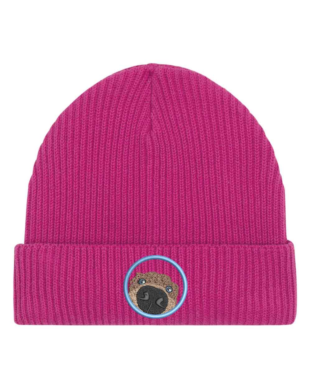 Căciulă roz din tricot cu manșetă întoarsă, brodată cu un patch circular cu față de pug, un accesoriu simpatic și jucăuș pentru iubitorii de câini.