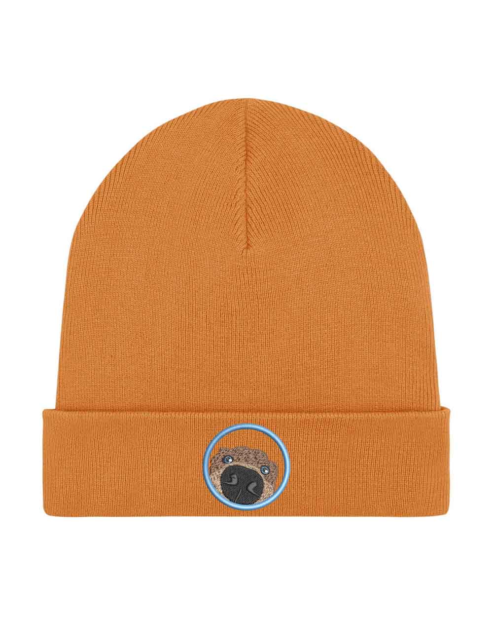 Căciulă portocalie din tricot cu manșetă întoarsă, brodată cu un patch circular cu față de pug, un accesoriu simpatic și jucăuș pentru iubitorii de câini.