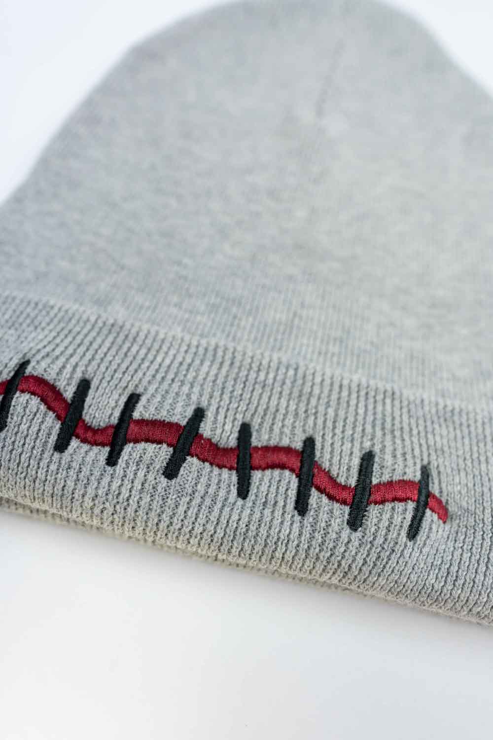 Căciulă gri din tricot cu manșetă întoarsă, brodată cu un design de cicatrice în roșu și negru, inspirat de efecte speciale și stil Halloween, un accesoriu original și îndrăzneț.