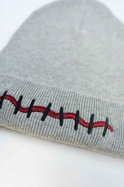 Căciulă gri din tricot cu manșetă întoarsă, brodată cu un design de cicatrice în roșu și negru, inspirat de efecte speciale și stil Halloween, un accesoriu original și îndrăzneț.