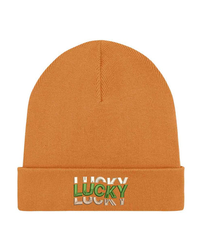 Căciulă portocalie din tricot reiat cu manșetă întoarsă, brodată cu mesajul „Lucky” în culori alb, verde și crem, un accesoriu modern și pozitiv pentru un stil casual.