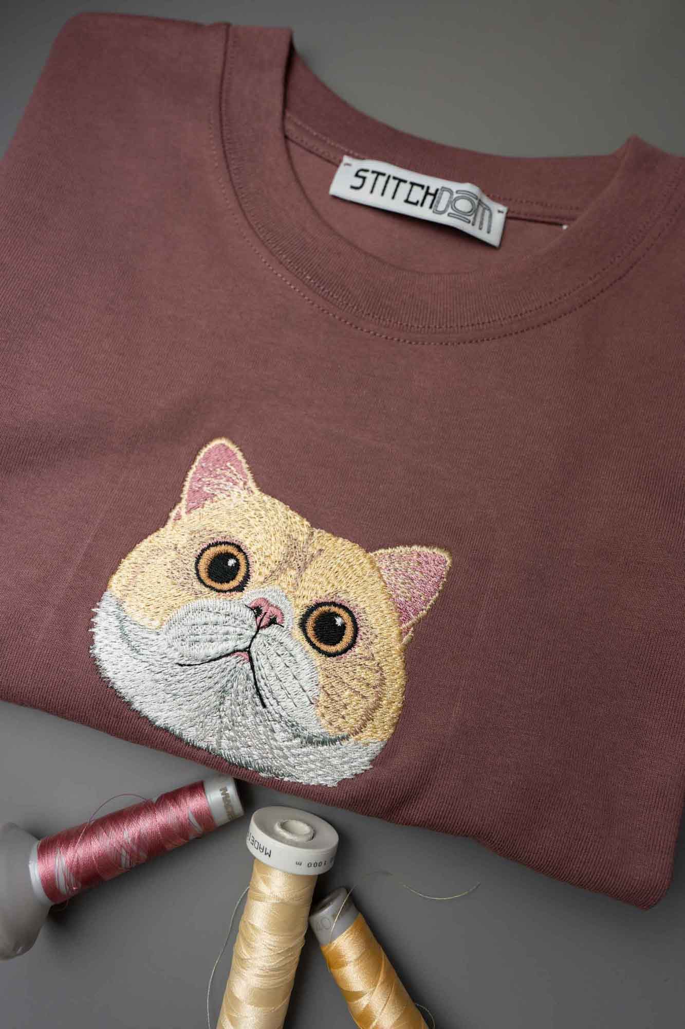 Tricou maro cu model brodat reprezentând fața unei pisici bej.