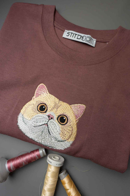Tricou maro cu model brodat reprezentând fața unei pisici bej.