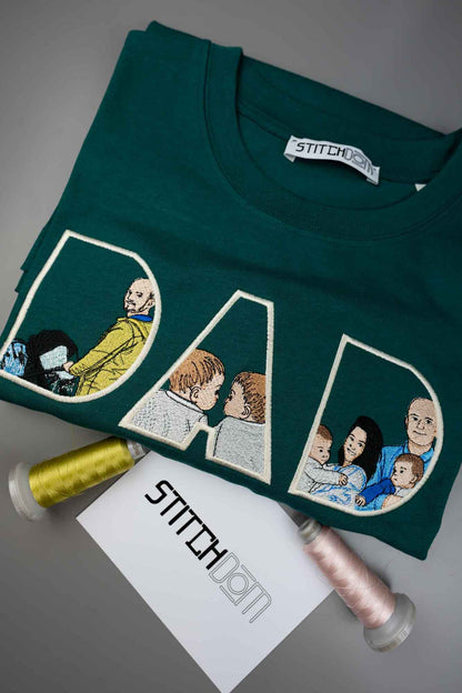 Tricou verde închis petrol împăturit, cu textul „DAD” brodat în litere mari conturate, fiecare literă conținând portrete brodate ale familiei, pe o suprafață gri, alături de două conuri de ață și un card branduit Stitchdom.