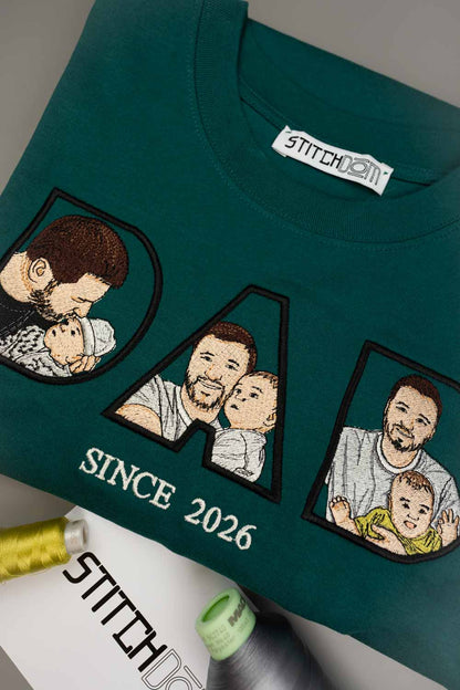 Tricou verde petrol închis din bumbac organic, împăturit, cu textul „DAD” brodat personalizat, cu poze de familie brodate în interiorul literelor, textul „SINCE 2026” și eticheta de brand „Stitchdom”.