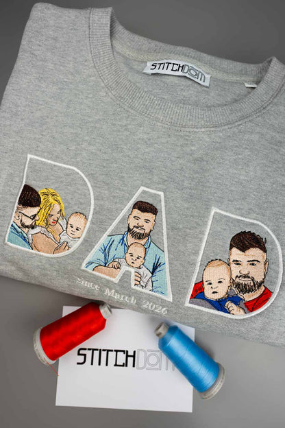 Bluza gri deschis melanj din bumbac organic, împăturit, cu textul „DAD” brodat și portrete brodate cu un tată și copiii săi, iar dedesubt textul „Since March 2026”.