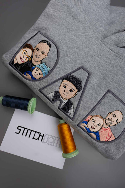 Hanorac gri deschis melanj din bumbac organic, împăturit, cu portrete de familie brodate în interiorul literelor „DAD”, reprezentate în stil cartoon, cu fețe cu ochelari, păr negru și haine colorate.