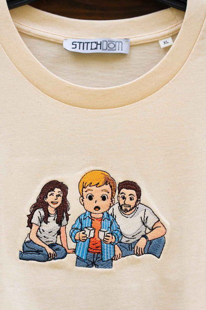 Tricou crem din bumbac organic, cu un model imprimat tip desen animat reprezentând trei personaje așezate împreună.