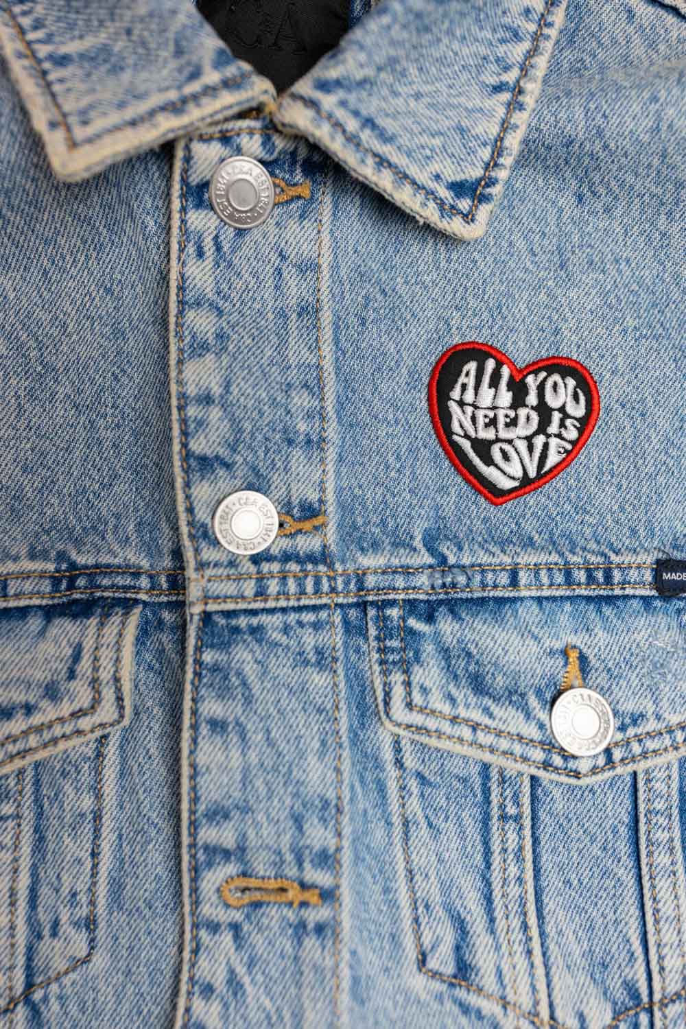 Patch brodat negru cu inimă roșie și mesajul „All You Need Is Love”, un accesoriu romantic și expresiv.
