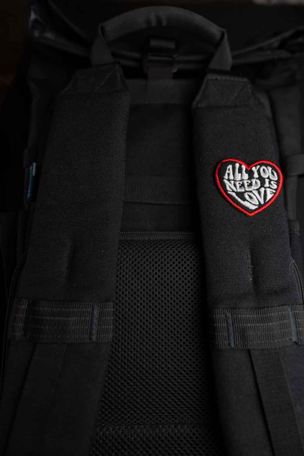 Patch brodat negru cu inimă roșie și mesajul „All You Need Is Love”, un accesoriu romantic și expresiv.
