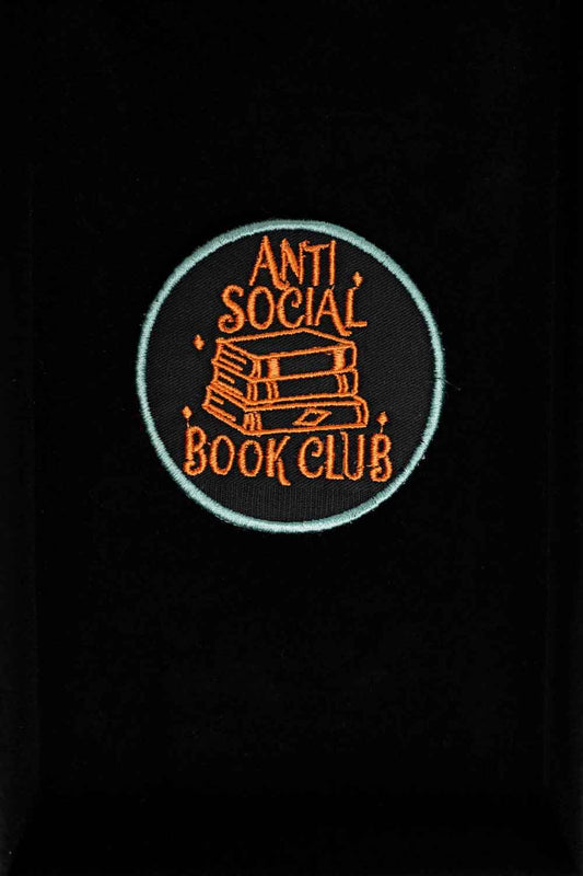 Patch brodat negru cu mesajul „Anti Social Book Club” și ilustrație de cărți, un accesoriu pentru pasionații de lectură.