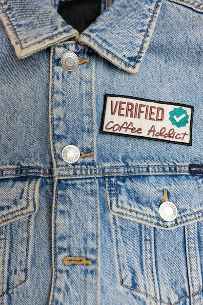 Patch brodat cu mesajul „Verified Coffee Addict” și simbol de verificare, un accesoriu perfect pentru iubitorii de cafea.