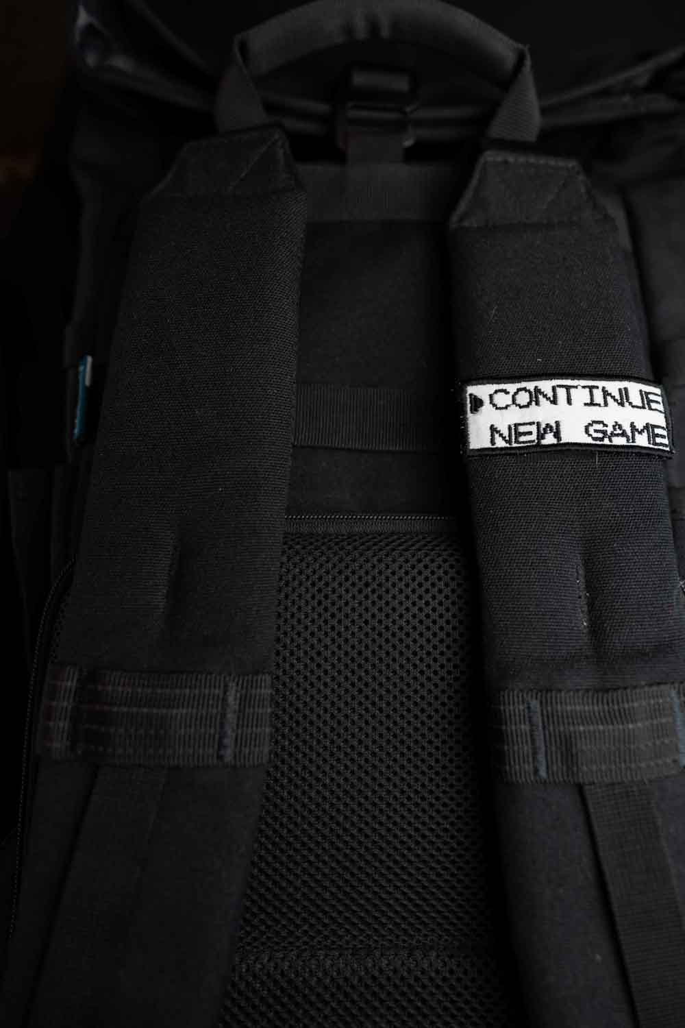 Patch brodat negru cu mesajul „Continue New Game”, un accesoriu inspirat de jocurile video retro.