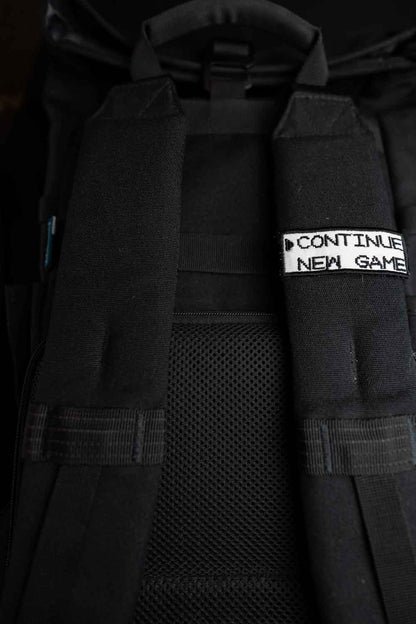 Patch brodat negru cu mesajul „Continue New Game”, un accesoriu inspirat de jocurile video retro.