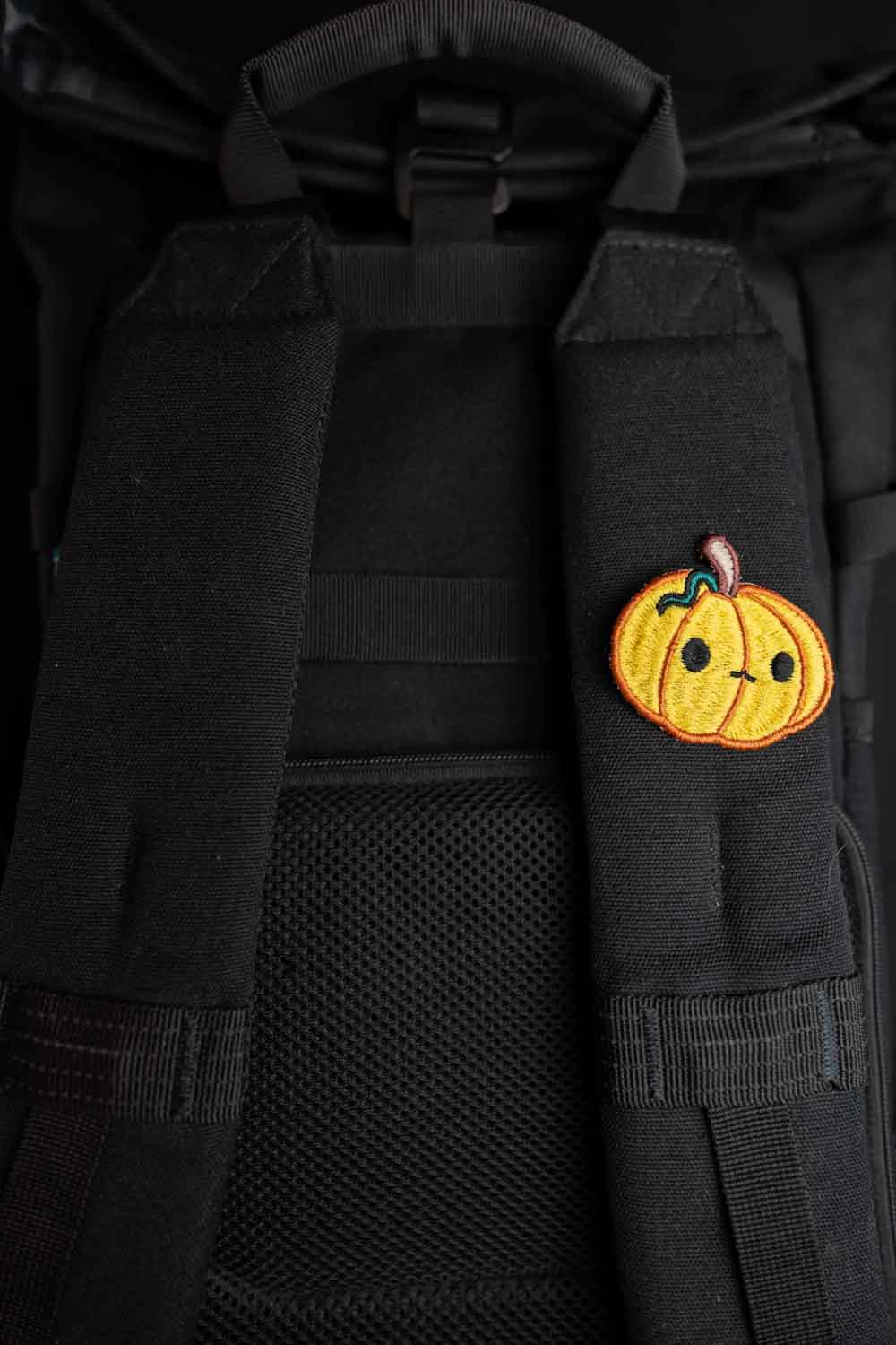 Patch brodat în formă de dovleac zâmbitor pe fundal negru, un accesoriu amuzant pentru Halloween, potrivit pentru personalizarea hainelor sau genților.
