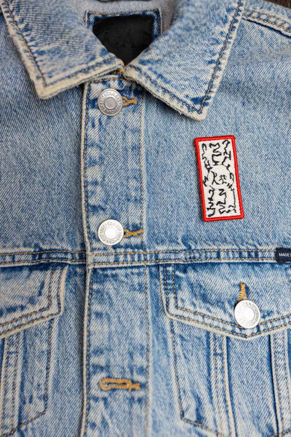 Patch brodat negru cu margine roșie și model floral alb în centru, un design elegant pentru personalizarea hainelor și accesoriilor.