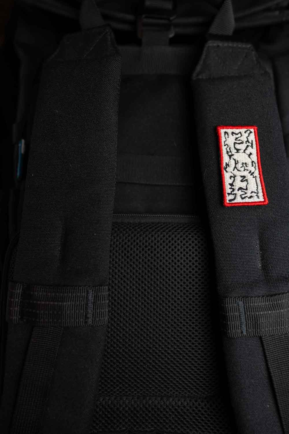 Patch brodat negru cu margine roșie și model floral alb în centru, un design elegant pentru personalizarea hainelor și accesoriilor.