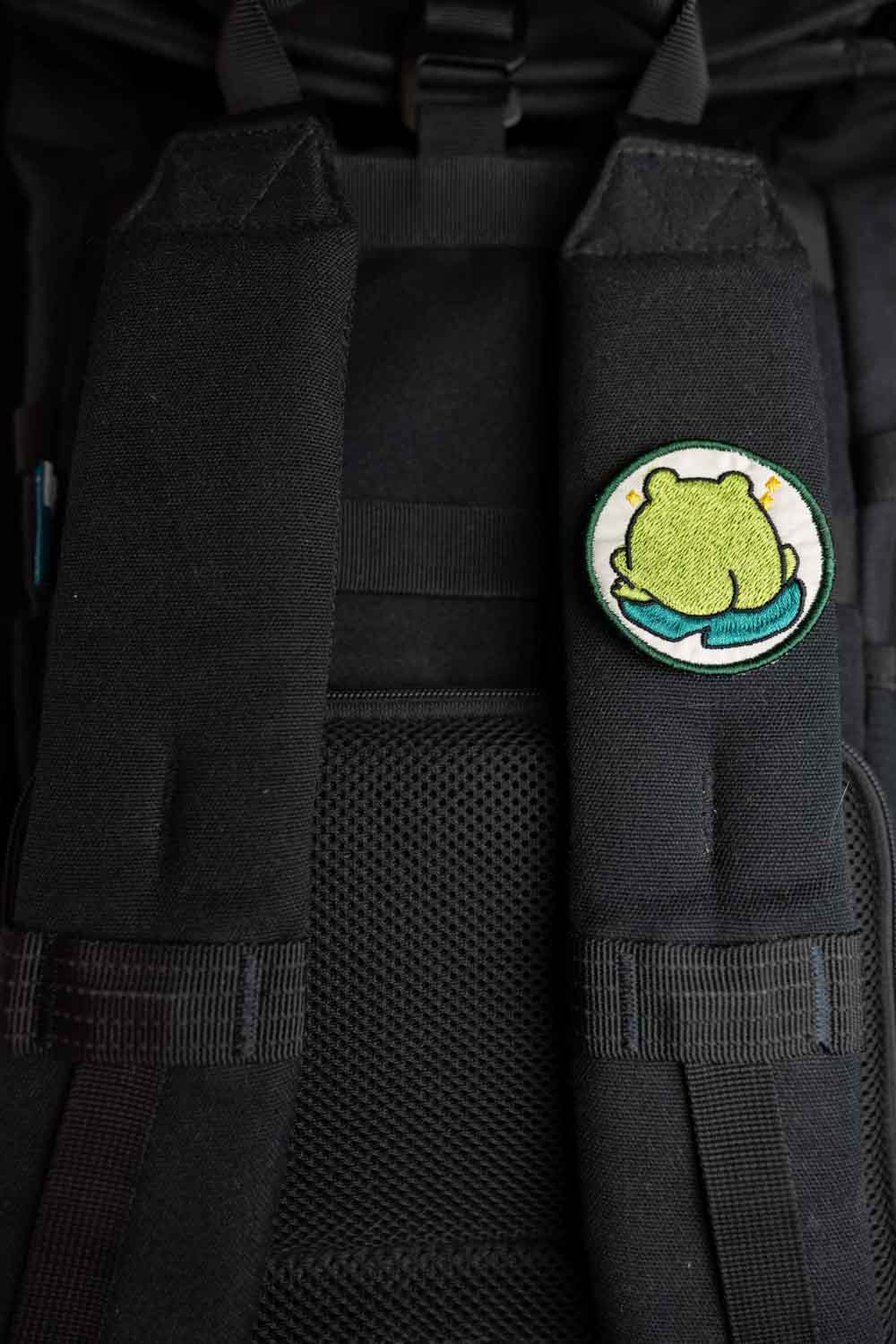 Patch brodat cu o broască stilizată așezată pe un nufăr, un accesoriu amuzant și colorat.