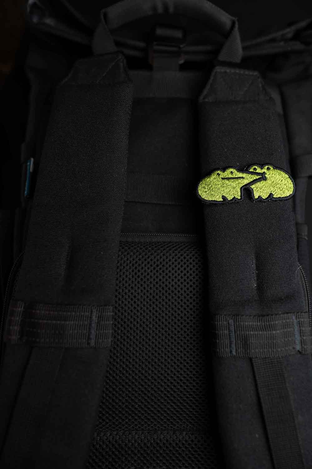 Patch brodat cu design de broască galbenă pe fundal negru, un accesoriu colorat și amuzant pentru haine, genți sau accesorii.