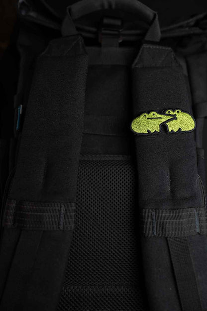 Patch brodat cu design de broască galbenă pe fundal negru, un accesoriu colorat și amuzant pentru haine, genți sau accesorii.