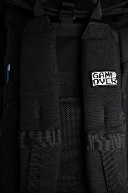 Patch brodat negru cu mesajul „Game Over” în alb, un accesoriu inspirat de jocurile video și cultura gaming.