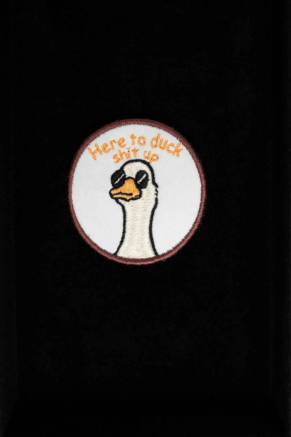Patch brodat rotund cu ilustrație de cap de rață și mesajul amuzant „Here to Duck Shit Up”, un accesoriu ironic și creativ.