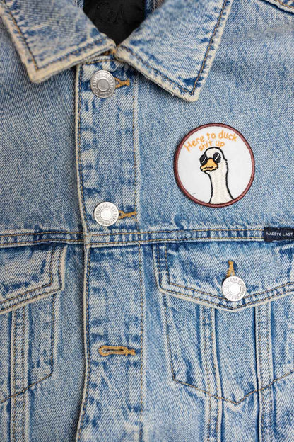 Patch brodat rotund cu ilustrație de cap de rață și mesajul amuzant „Here to Duck Shit Up”, un accesoriu ironic și creativ.