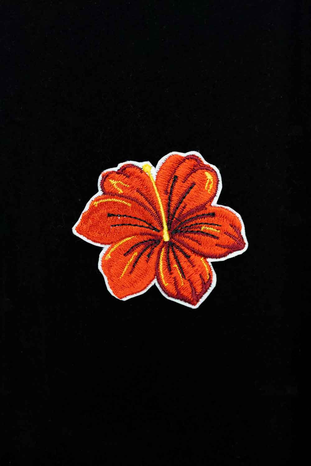Broșă brodată cu floare de hibiscus, un accesoriu elegant cu influențe tropicale și culori vibrante.