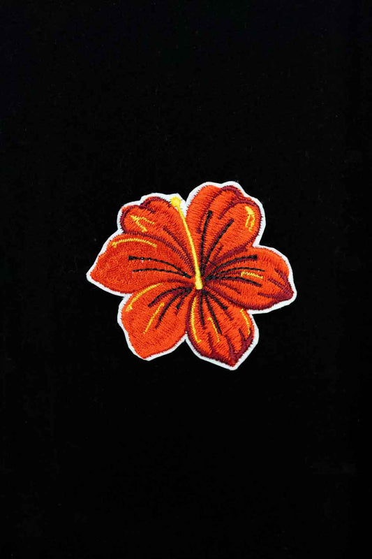 Broșă brodată cu floare de hibiscus, un accesoriu elegant cu influențe tropicale și culori vibrante.