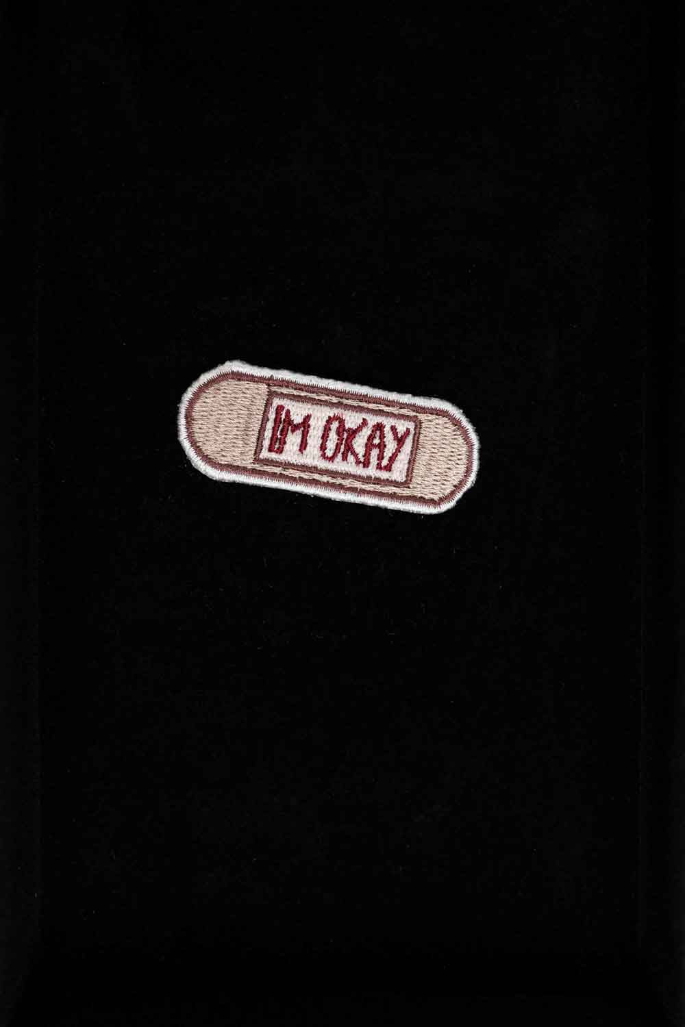 Patch brodat cu mesajul „I'm Okay” pe fundal bej, un accesoriu minimalist cu mesaj ironic și expresiv.