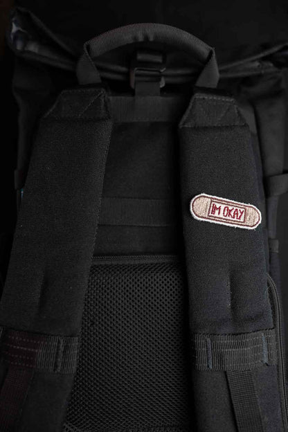 Patch brodat cu mesajul „I'm Okay” pe fundal bej, un accesoriu minimalist cu mesaj ironic și expresiv.