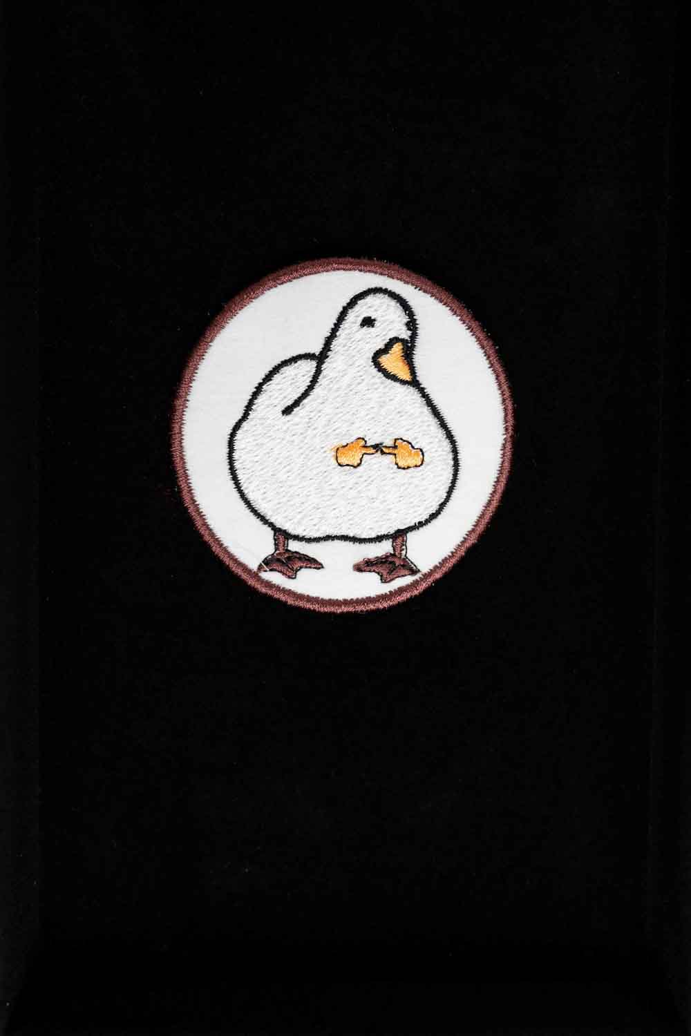 Patch brodat rotund cu fundal alb și roșu și o rață albă stilizată în centru, un accesoriu kawaii și colorat.