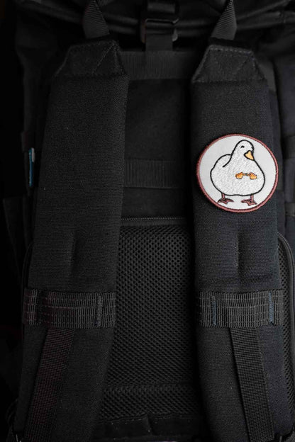 Patch brodat rotund cu fundal alb și roșu și o rață albă stilizată în centru, un accesoriu kawaii și colorat.