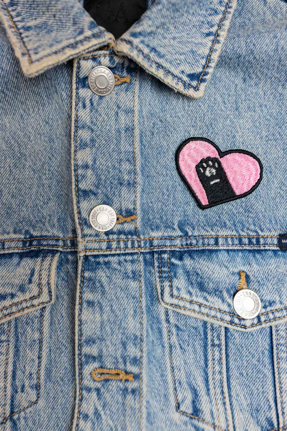 Patch brodat cu design în formă de inimă și o lăbuță neagră în centru, un accesoriu simpatic pentru iubitorii de animale.