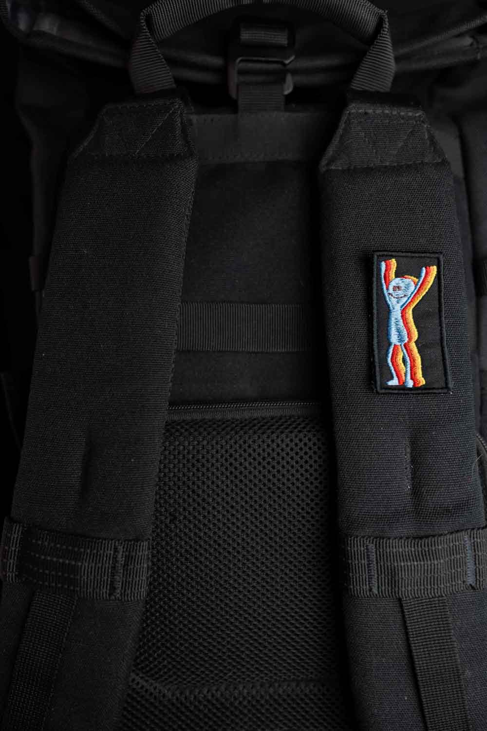 Patch brodat colorat cu un personaj care ține mâinile ridicate, design vesel și amuzant, un accesoriu ideal pentru personalizarea hainelor, genților sau accesoriilor.