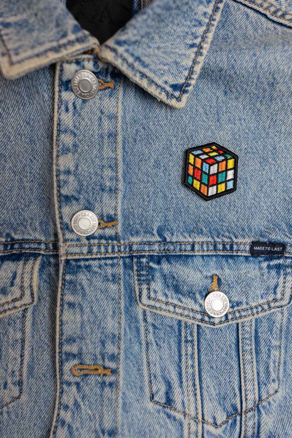 Patch brodat cu design de cub Rubik colorat pe fundal negru, un accesoriu inspirat de jocurile clasice.