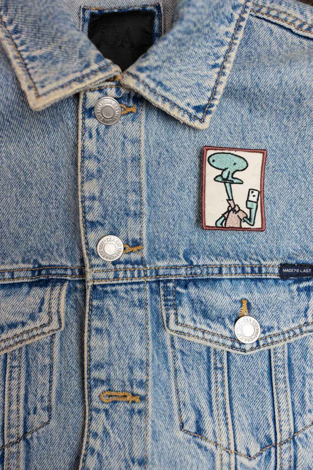 Patch brodat cu design amuzant inspirat de Patrick din SpongeBob, ținând o cameră foto pentru selfie, în culori roz și alb, un accesoriu creativ pentru personalizare.