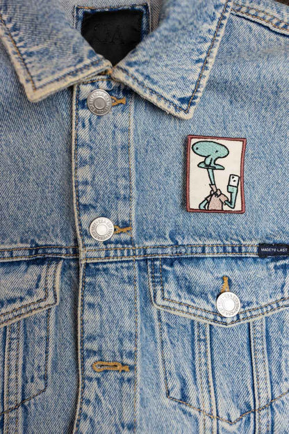 Patch brodat cu design amuzant inspirat de Patrick din SpongeBob, ținând o cameră foto pentru selfie, în culori roz și alb, un accesoriu creativ pentru personalizare.