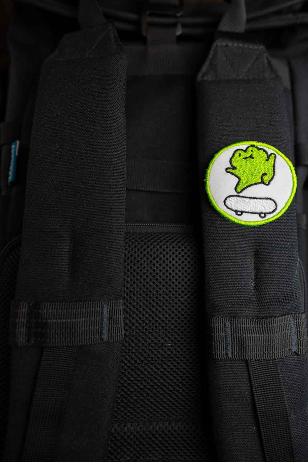 Patch brodat cu personaj stilizat pe skateboard, în culori verde și alb pe fundal negru, un accesoriu pentru iubitorii de skate.