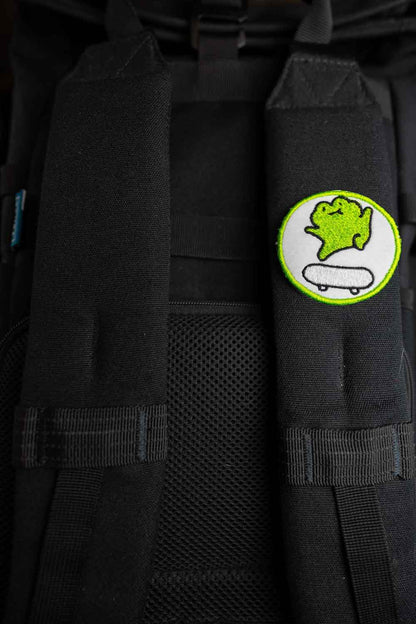 Patch brodat cu personaj stilizat pe skateboard, în culori verde și alb pe fundal negru, un accesoriu pentru iubitorii de skate.