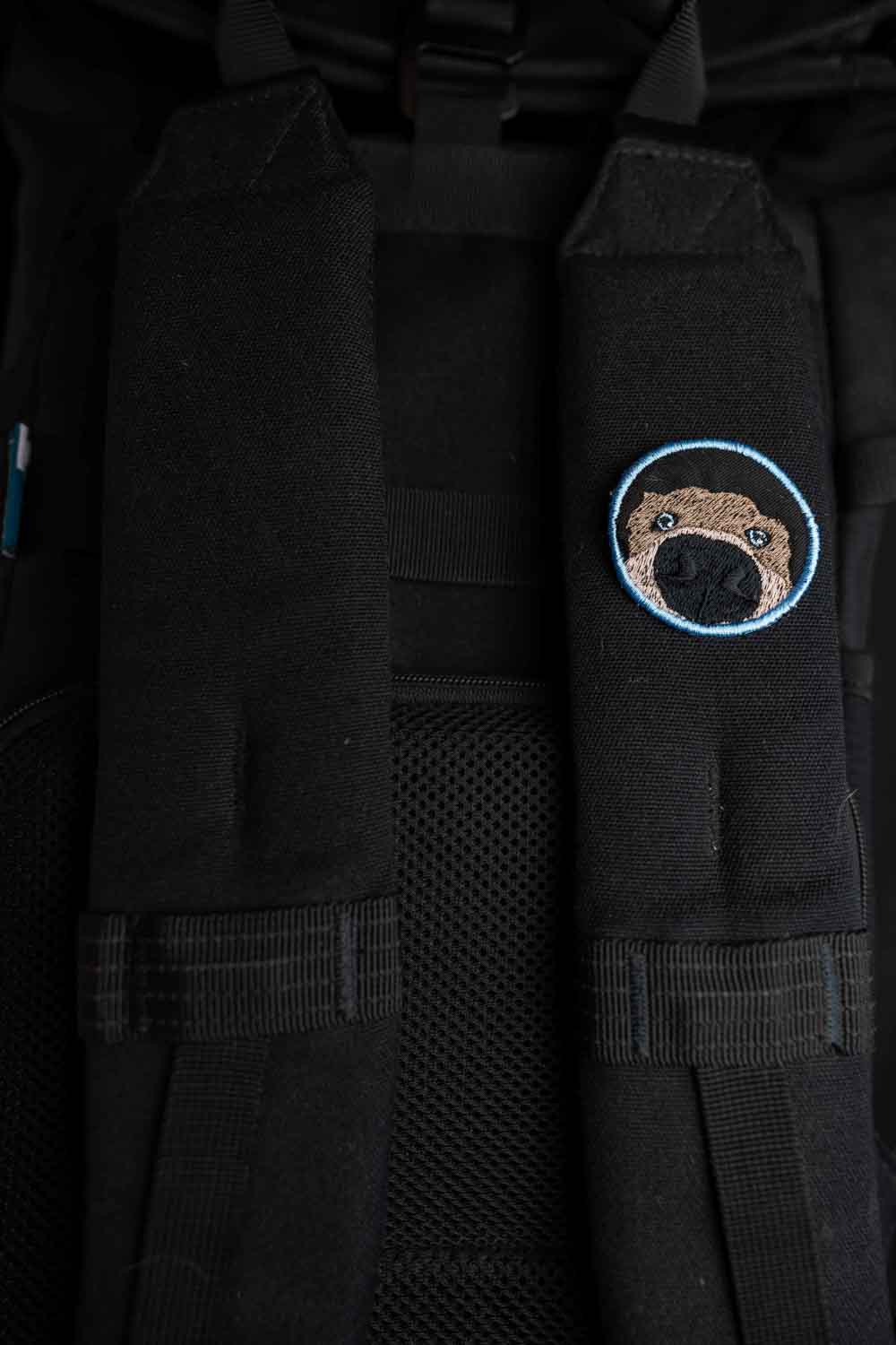 Patch brodat rotund cu față de câine în centru pe fundal negru, un accesoriu amuzant pentru iubitorii de animale.