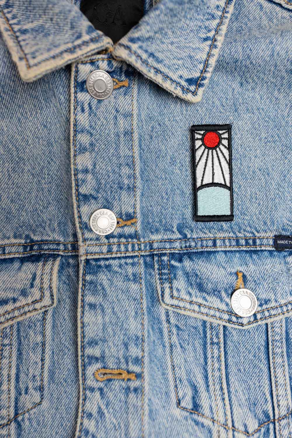 Patch brodat inspirat de universul anime, cu design roșu și alb asemănător unui simbol solar, un accesoriu pentru fanii culturii japoneze.