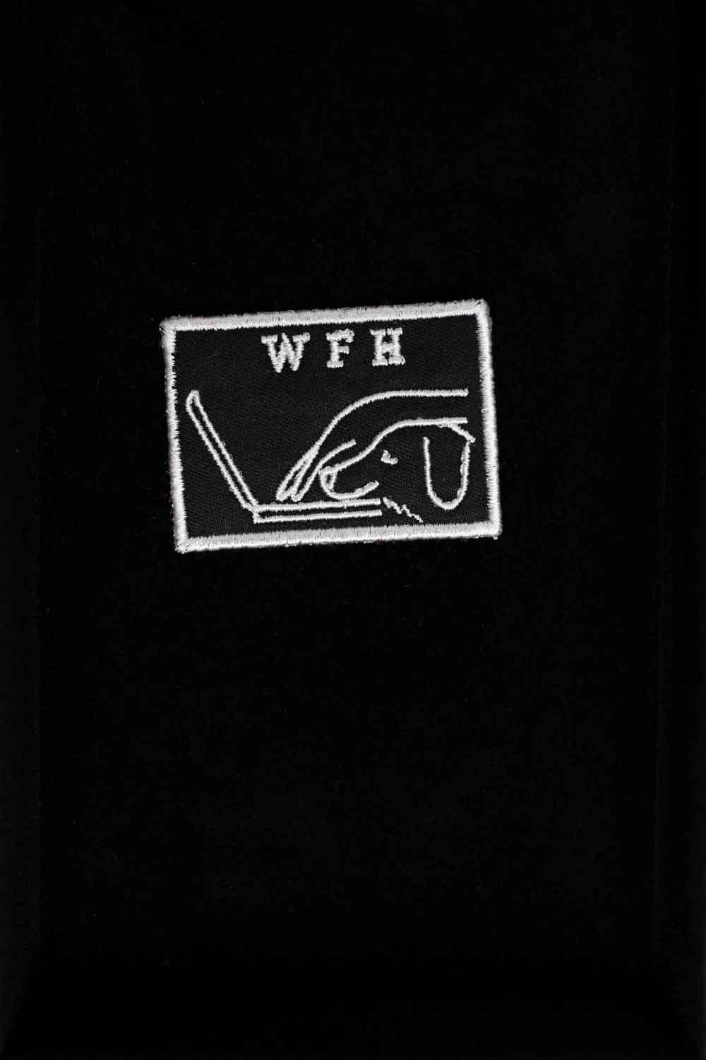 Patch brodat negru cu mesajul „WFH” și ilustrație de persoană cu laptop, un accesoriu pentru iubitorii muncii de acasă.