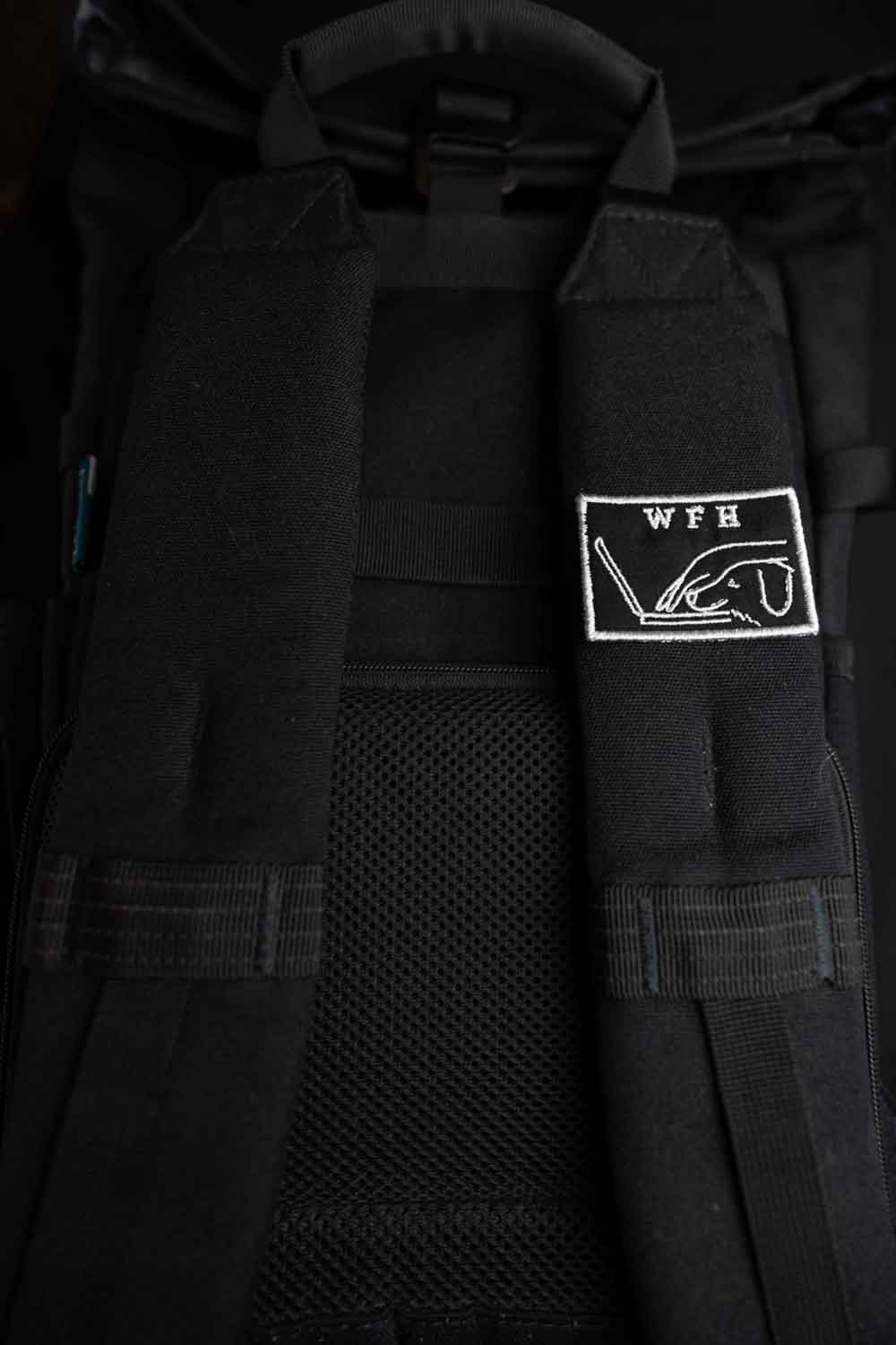 Patch brodat negru cu mesajul „WFH” și ilustrație de persoană cu laptop, un accesoriu pentru iubitorii muncii de acasă.