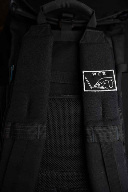 Patch brodat negru cu mesajul „WFH” și ilustrație de persoană cu laptop, un accesoriu pentru iubitorii muncii de acasă.